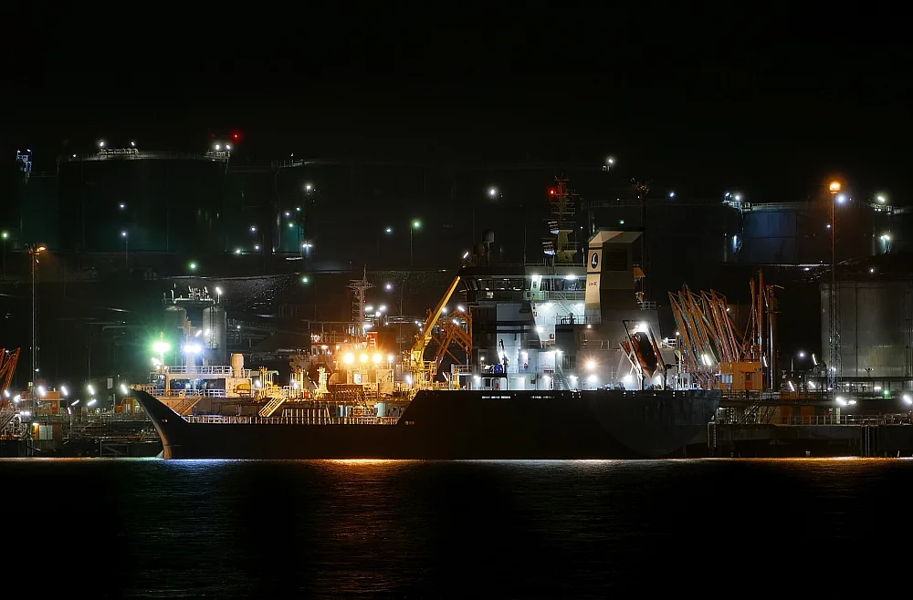 Product terminal illuminated at night with a tanker alongside the jetty