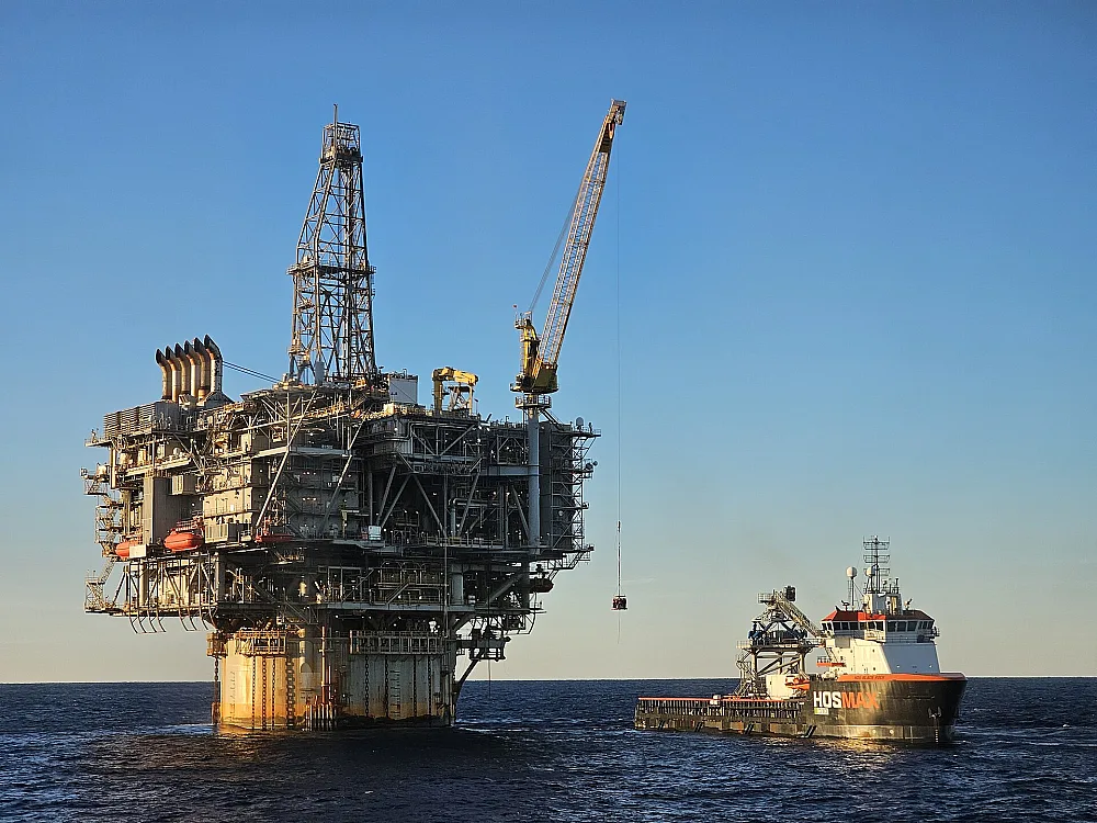 Offshore production platform and supply vessel at golden hour